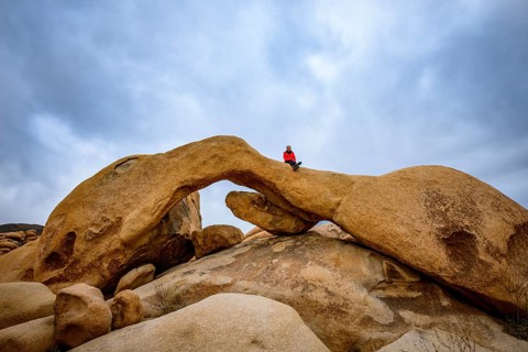 Young woman sits on Arch Rock