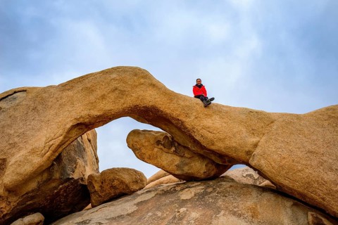Young woman sits on Arch Rock