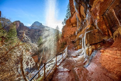 Waterfall falls from overhanging rock in winter
