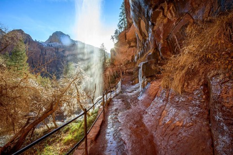 Waterfall falls from overhanging rock in winter