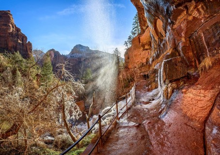 Waterfall falls from overhanging rock in winter