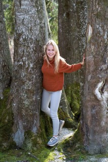 Young woman with long blond hair between trees