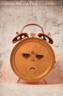 Back of an alarm clock in the shape of a frowning face