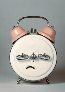 Back of an alarm clock in the shape of a frowning face