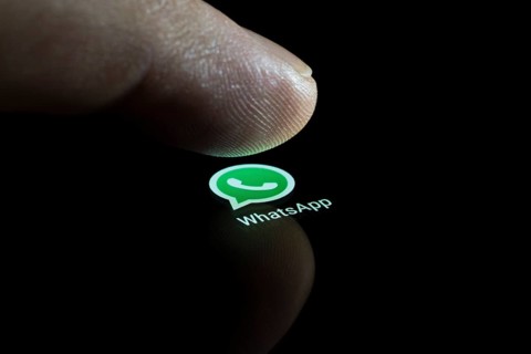 WhatsApp app icon on a display with finger