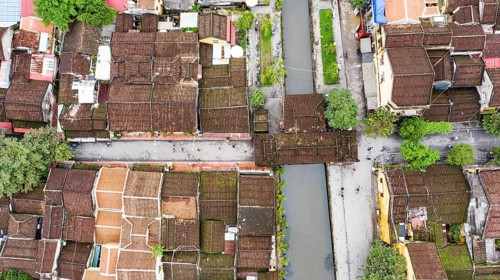 Roofs of old houses with Japanese Covered Bridge or Cau Chua Pagoda in Hoi An ancient town