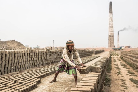 Workers of a brickyard stacking dried bricks