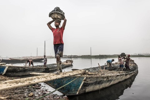 Workers unload clay from a boat