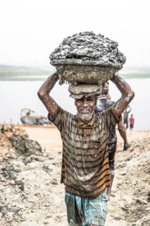 Brickyard worker carrying clay in basket on his head