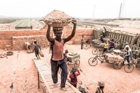 Brickyard worker carrying basket of ashes on his head