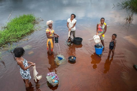 Women washing clothes by the river Ntem in the rainforest