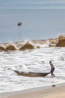Fisherman with a dugout canoe on the beach