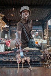 Seller grilling meat at street stand