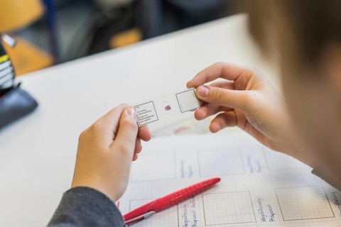 Student holding microscope specimen in hand