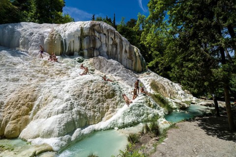 Accumulated white minerals and the pools of the hot springs of Bagni San Filippo in the middle of the forest