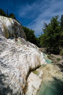 Accumulated white minerals and the pools of the hot springs of Bagni San Filippo in the middle of the forest