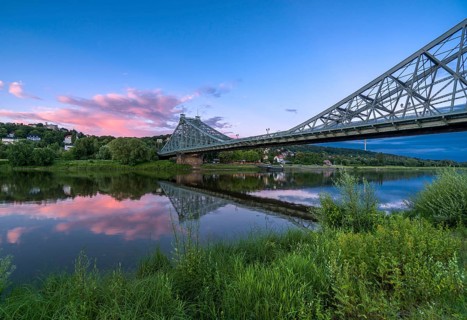 Historical bridge Blaues Wunder is crossing the river Elbe at dust with red cloud above it