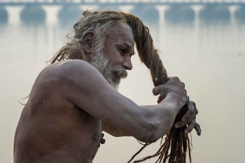 Sadhu drying his dreadlocks on Ganges riverbank