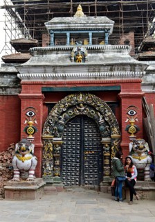 Two Nepalese girls looking at a mobile phone at the gate to Taleju Temple