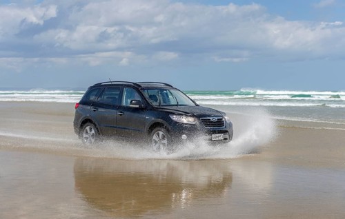 Black Hyundai Santa Fe 4x4 off-road vehicle drives on the sandy beach of Ninety Mile Beach in the water