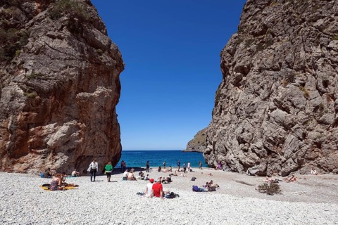 People sunbathe on the beach in the gorge Torrent de Pareis