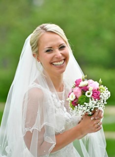 Laughing bride in white wedding dress with bridal bouquet and veil