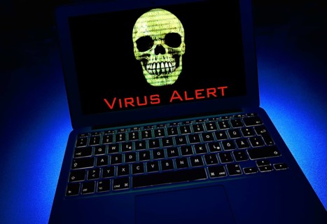 Laptop with skull and crossbones and binary numbers on screen