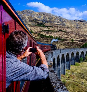 Man leans out the window taking a picture of historic train
