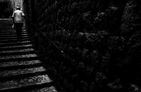 Old man climbs stairs in old town. Fornalutx