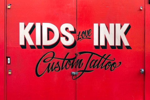 Painted sign for Kids Love Ink tattoo parlor