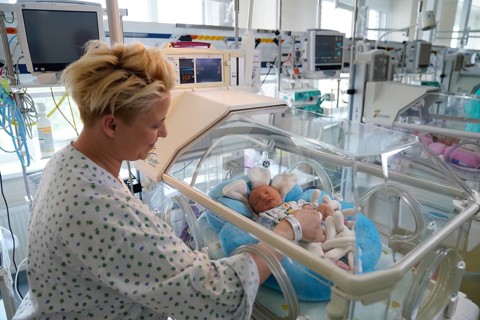 Mother of twins with one of her newborns in an incubator
