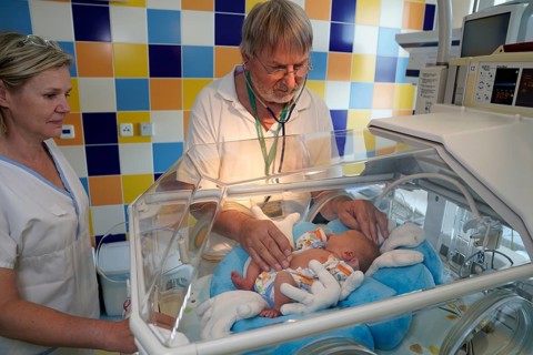 Doctor and nurse examining a newborn in an incubator