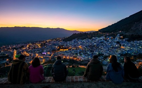 People sitting on a wall overlooking city Chefchaouen