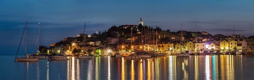 View of the town with sailing boats and lights reflecting in the water