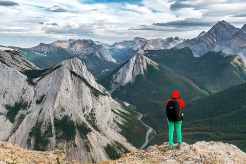 Female hiker views from summit over mountain landscape