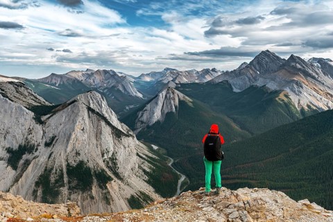 Female hiker views from summit over mountain landscape
