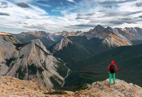 Female hiker looks from summit over mountain landscape