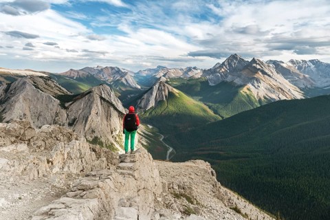 Female hiker views from summit over mountain landscape