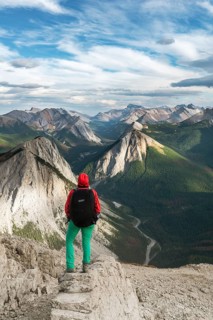Female hiker views from summit over mountain landscape