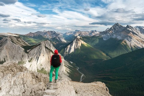 Female hiker views from summit over mountain landscape