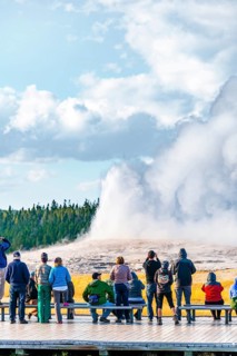 Tourists observe eruption of Old Faithful Geyser