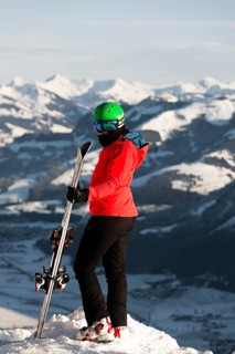 Female skier with ski helmet standing with ski at the ski slope above the valley