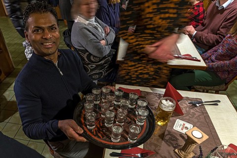 Waiter holds a tray of full Ouzoglasses in a restaurant