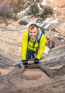 Young smiling hiker climbs wooden ladder
