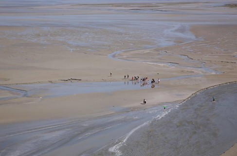 Hikers in mudflat at low tide in Mont Saint Michel
