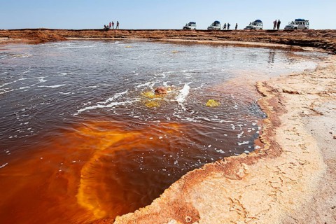 Tourists near salt lake with geothermal springs and petrified salt crystals