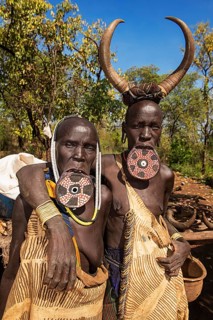 Two women with large lip plates and horns as headdress