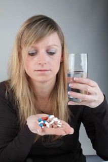 Young woman holding a large amount of pills in her hand