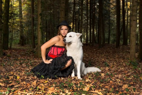 Blonde woman with white shepherd dog in the forest