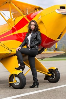 Young woman with leather jacket poses with yellow double-decker aviator